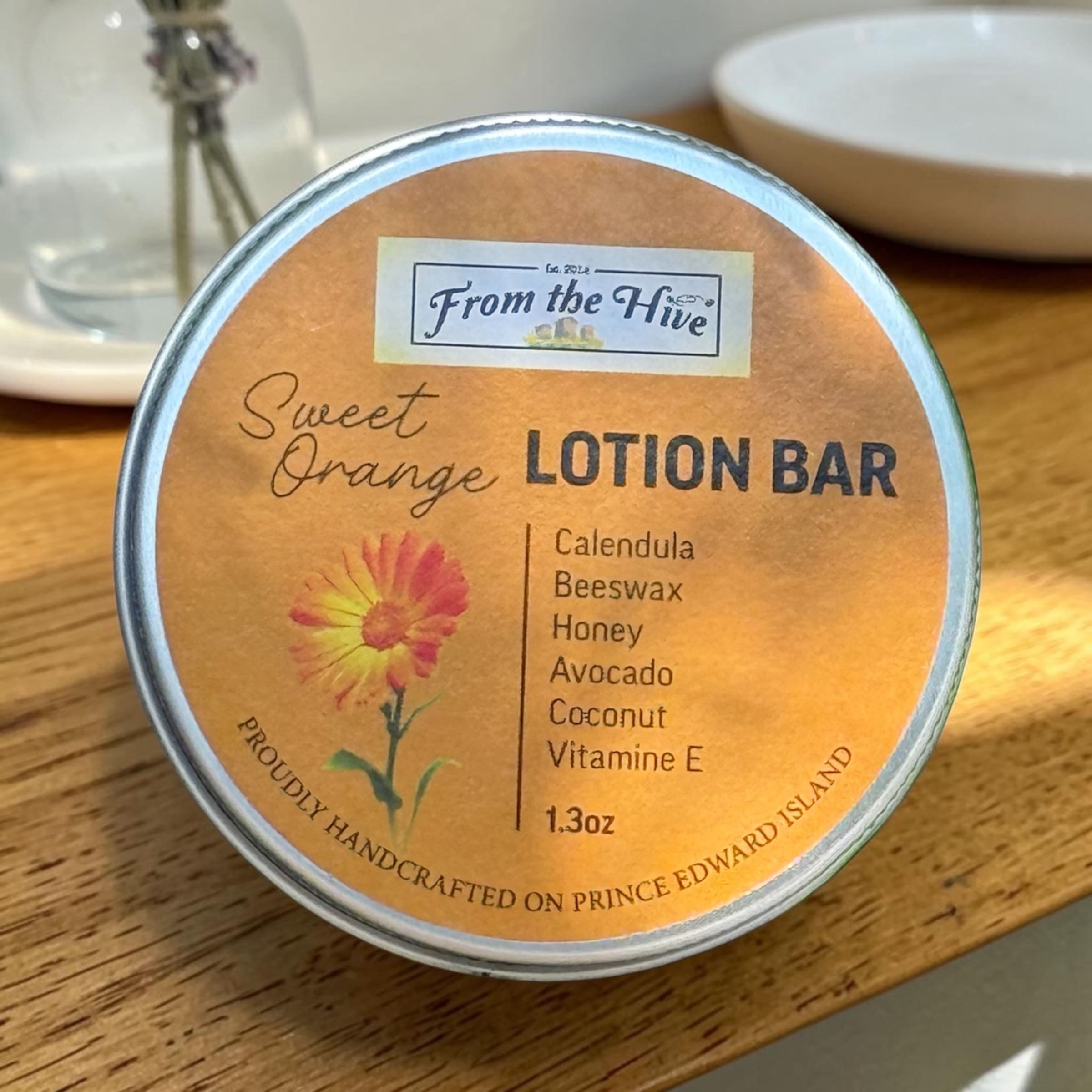 Sweet Orange Calendula Honey moisturizing lotion bar with a honey bee imprint. A 60ml (2oz.) silver aluminum tin with screw top holds a 1.3oz solid bar.